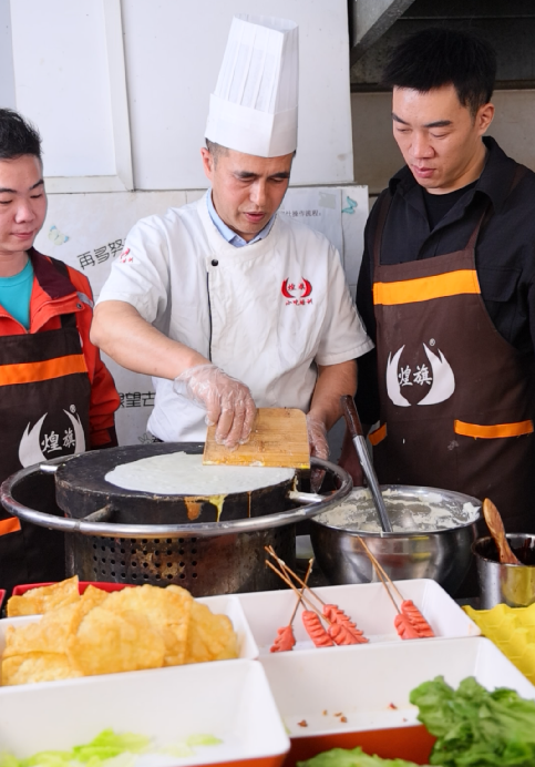 “煌旗煎饼果子师傅摊饼中”/